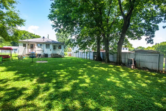 a view of a house with a big yard and large trees