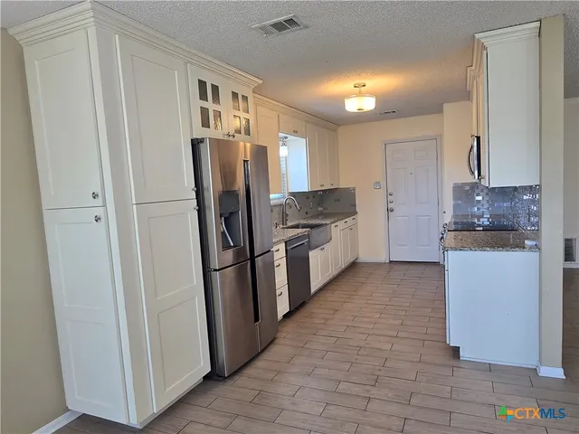 a kitchen with stainless steel appliances granite countertop a refrigerator and a sink