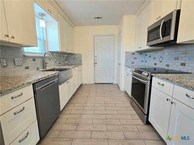 a kitchen with stainless steel appliances granite countertop a stove a sink and a microwave
