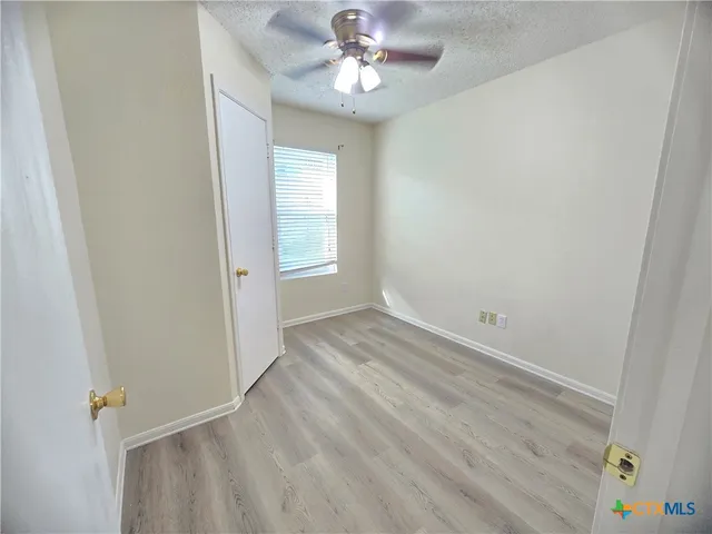 an empty room with windows and fan