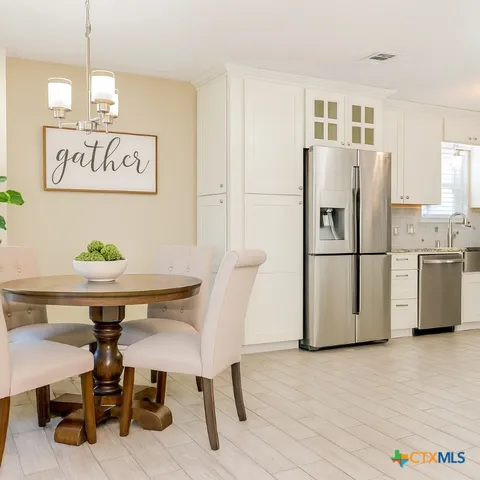 a view of kitchen with stainless steel appliances granite countertop a dining table and chairs