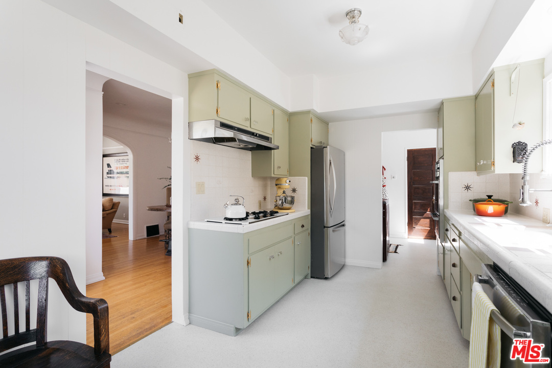 6151 Barrows Drive Los Angeles, CA 90048 - Photo 9 of 25 a kitchen with stainless steel appliances a stove a refrigerator a sink a dining table and chairs