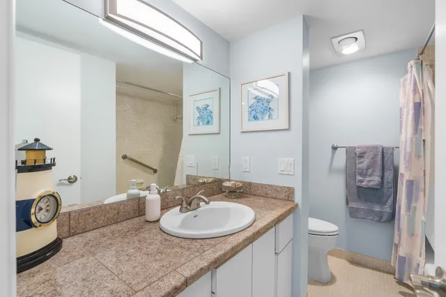 a bathroom with a granite countertop sink a toilet a mirror and shower
