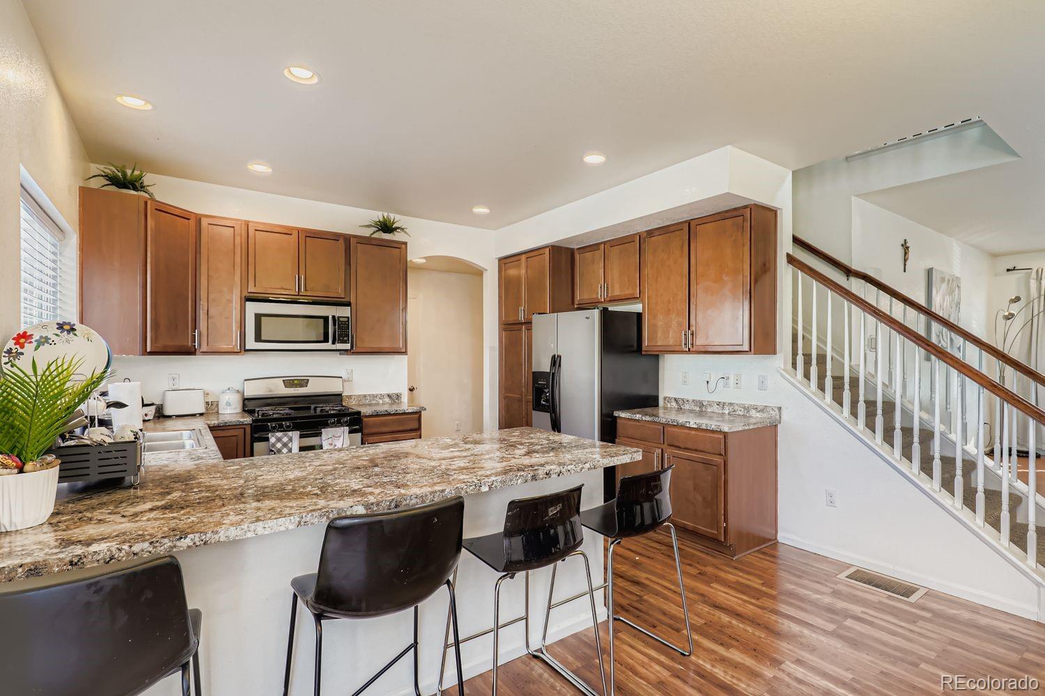 5545 Liverpool Street Denver, CO 80249 - Photo 13 of 28 a kitchen with stainless steel appliances granite countertop a stove refrigerator sink and cabinets
