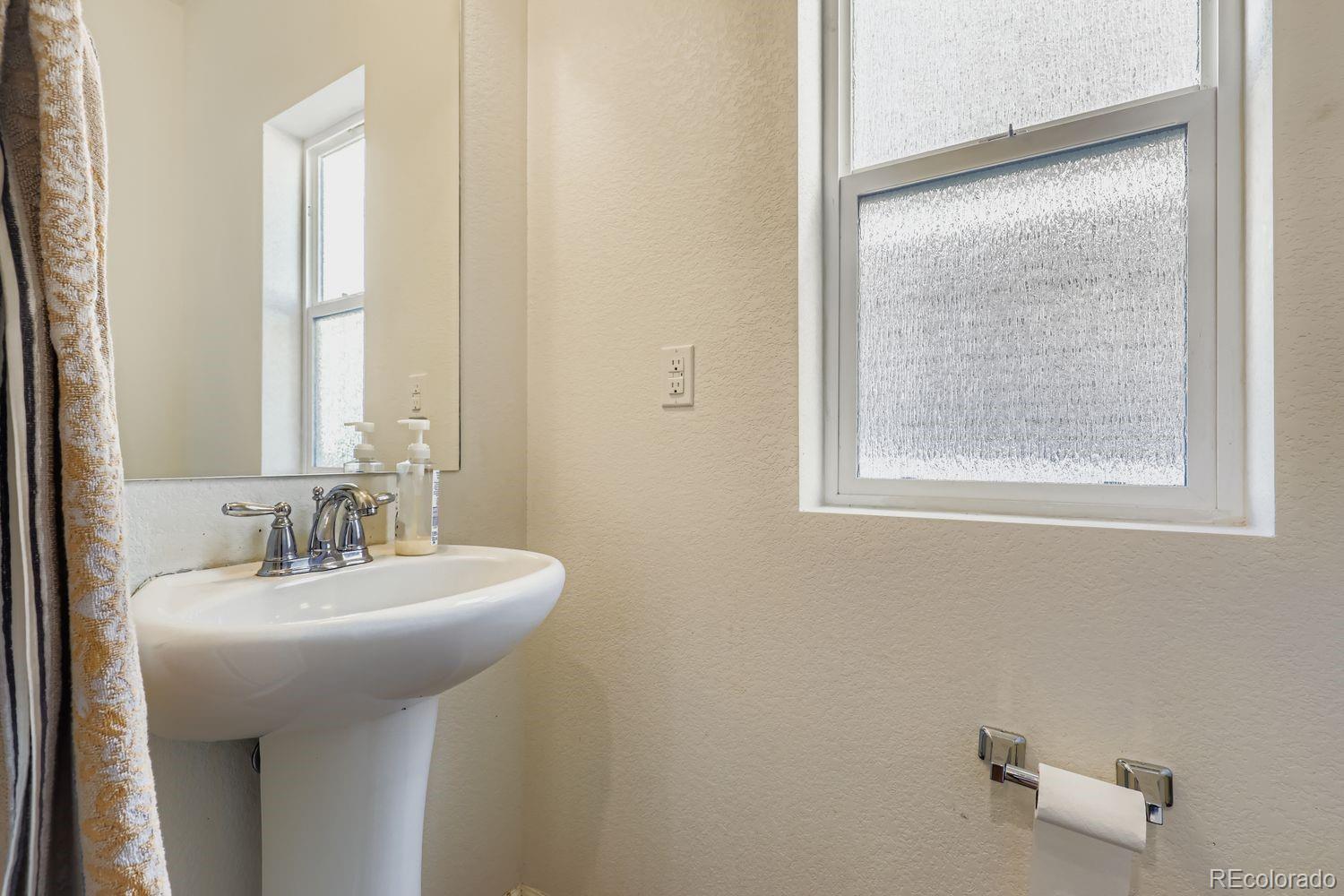5545 Liverpool Street Denver, CO 80249 - Photo 14 of 28 a bathroom with a sink a mirror and a window