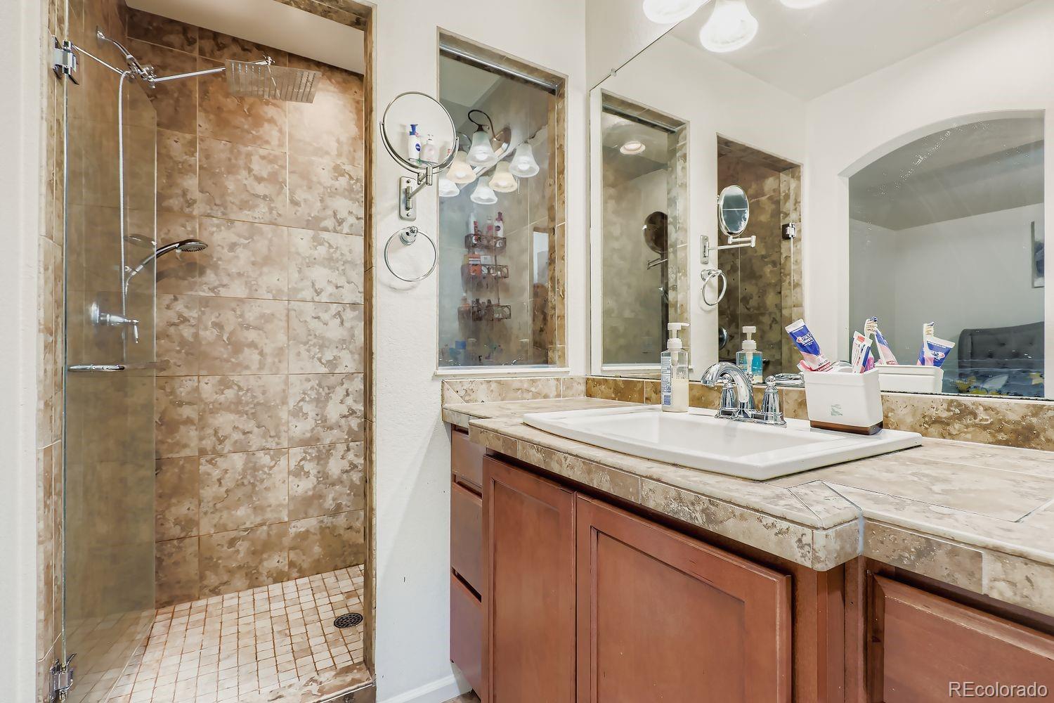 5545 Liverpool Street Denver, CO 80249 - Photo 17 of 28 a bathroom with a granite countertop sink mirror and shower