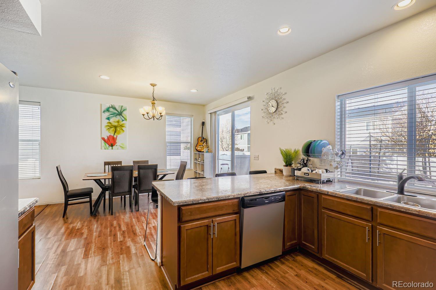 5545 Liverpool Street Denver, CO 80249 - Photo 10 of 28 a kitchen with a sink dining table chairs and wooden floor