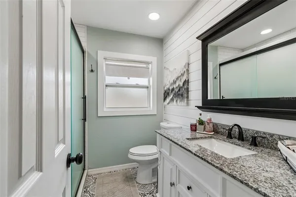 a bathroom with a granite countertop sink toilet and mirror