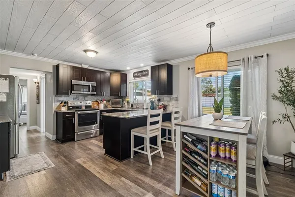 a kitchen with stainless steel appliances granite countertop a stove refrigerator and a dining table with wooden floor
