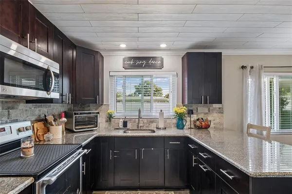 a kitchen with stainless steel appliances granite countertop a sink a stove cabinets counter space and a window