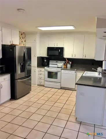 a kitchen with a refrigerator sink and cabinets
