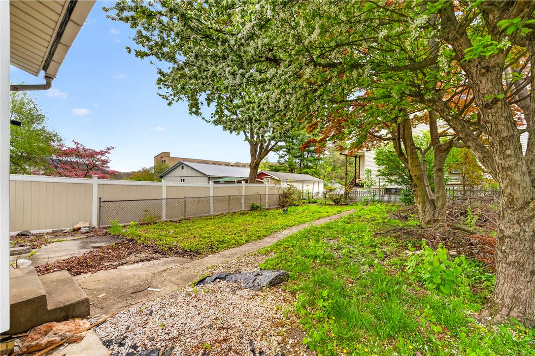 65 2nd Street Slatington, PA 18080 - Photo 43 of 46 Mature trees and vibrant green landscaping define this spacious backyard with a fence, offering privacy and a tranquil outdoor setting.