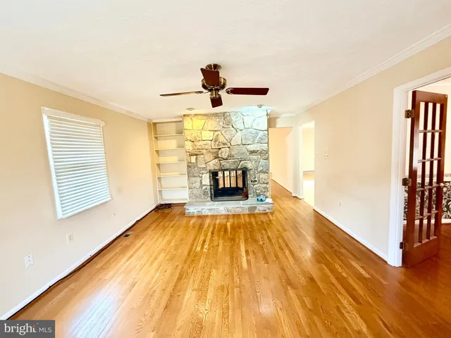 a view of an empty room with wooden floor and a kitchen