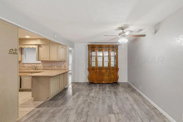 a large white kitchen with a sink dishwasher and a fireplace with wooden floor