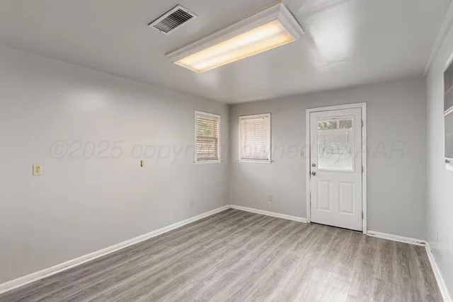 an empty room with a wooden floor and windows