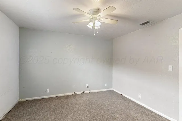 an empty room with a chandelier fan and a window
