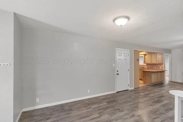 a view of an empty room and window and wooden floor