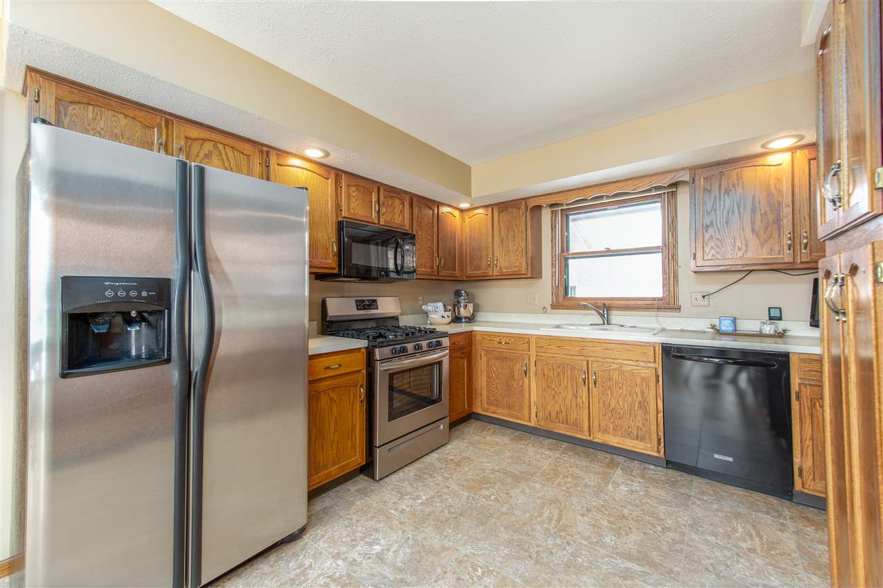 7339 East Wildwood Road Stillman Valley, IL 61084 - Photo 17 of 40 a kitchen with stainless steel appliances granite countertop a refrigerator a stove top oven a sink and dishwasher with wooden floor
