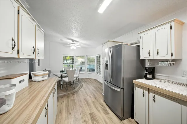 a kitchen with granite countertop a refrigerator a sink a stove and white cabinets