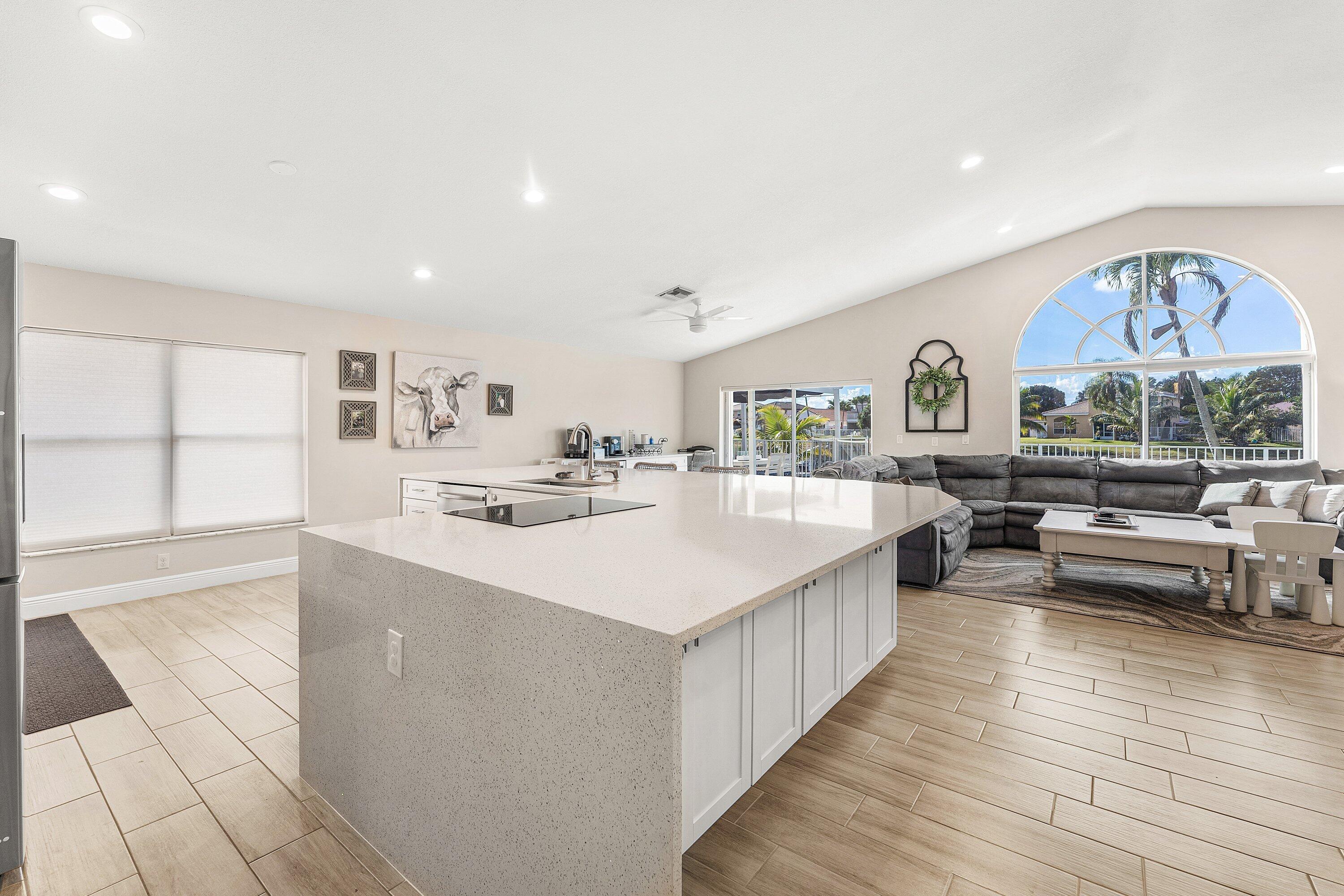 7346 Michigan Isle Road Lake Worth, FL 33467 - Photo 11 of 44 a living room with stainless steel appliances kitchen island granite countertop a large kitchen counter top and couches with wooden floor