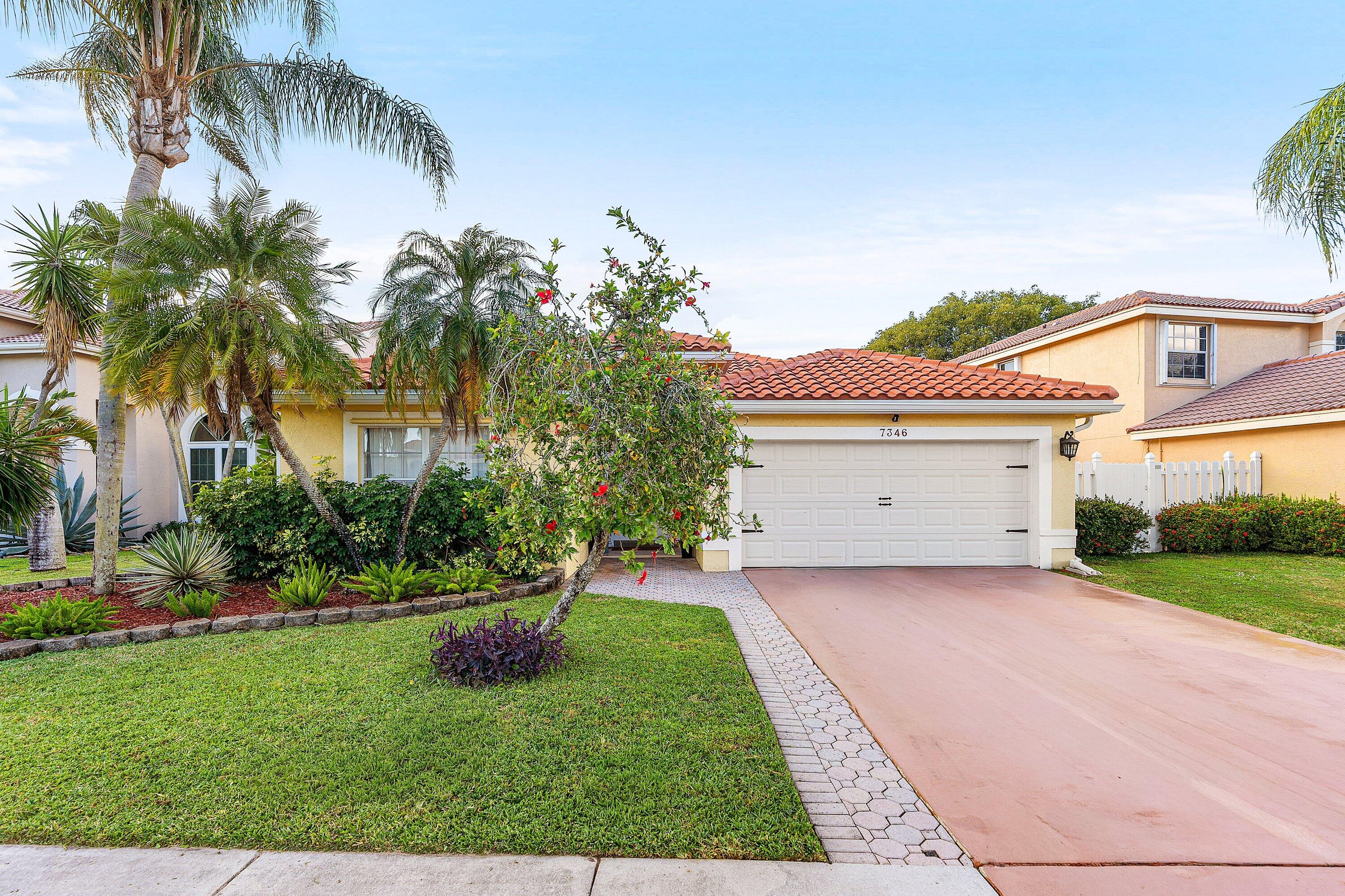 7346 Michigan Isle Road Lake Worth, FL 33467 - Photo 3 of 44 a front view of a house with a yard and garage