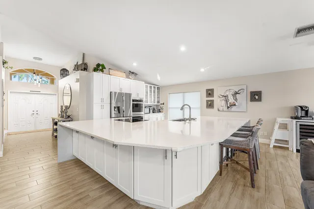 a large white kitchen with kitchen island a stove a table and chairs