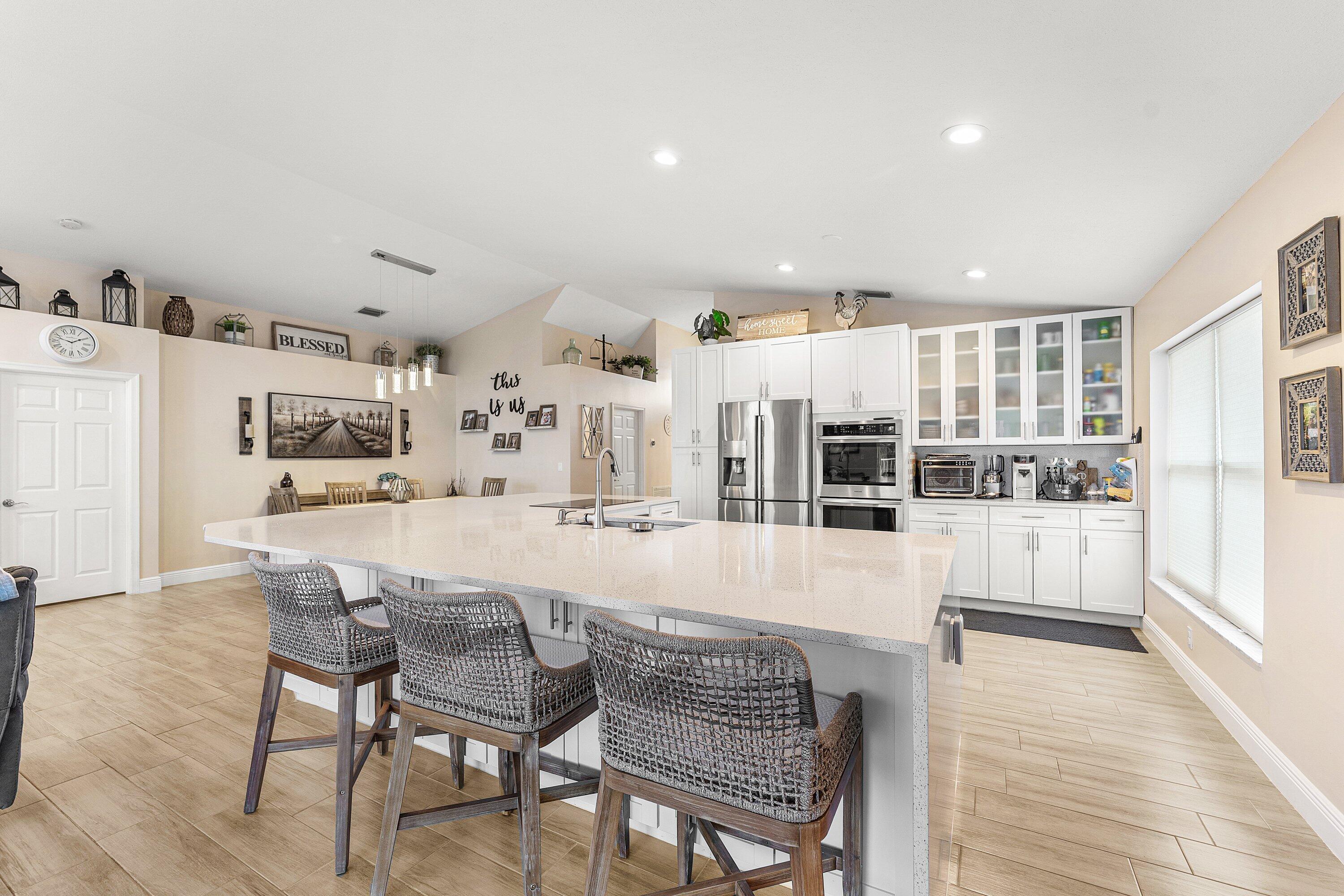 7346 Michigan Isle Road Lake Worth, FL 33467 - Photo 5 of 44 a dining room with stainless steel appliances kitchen island granite countertop a table and chairs