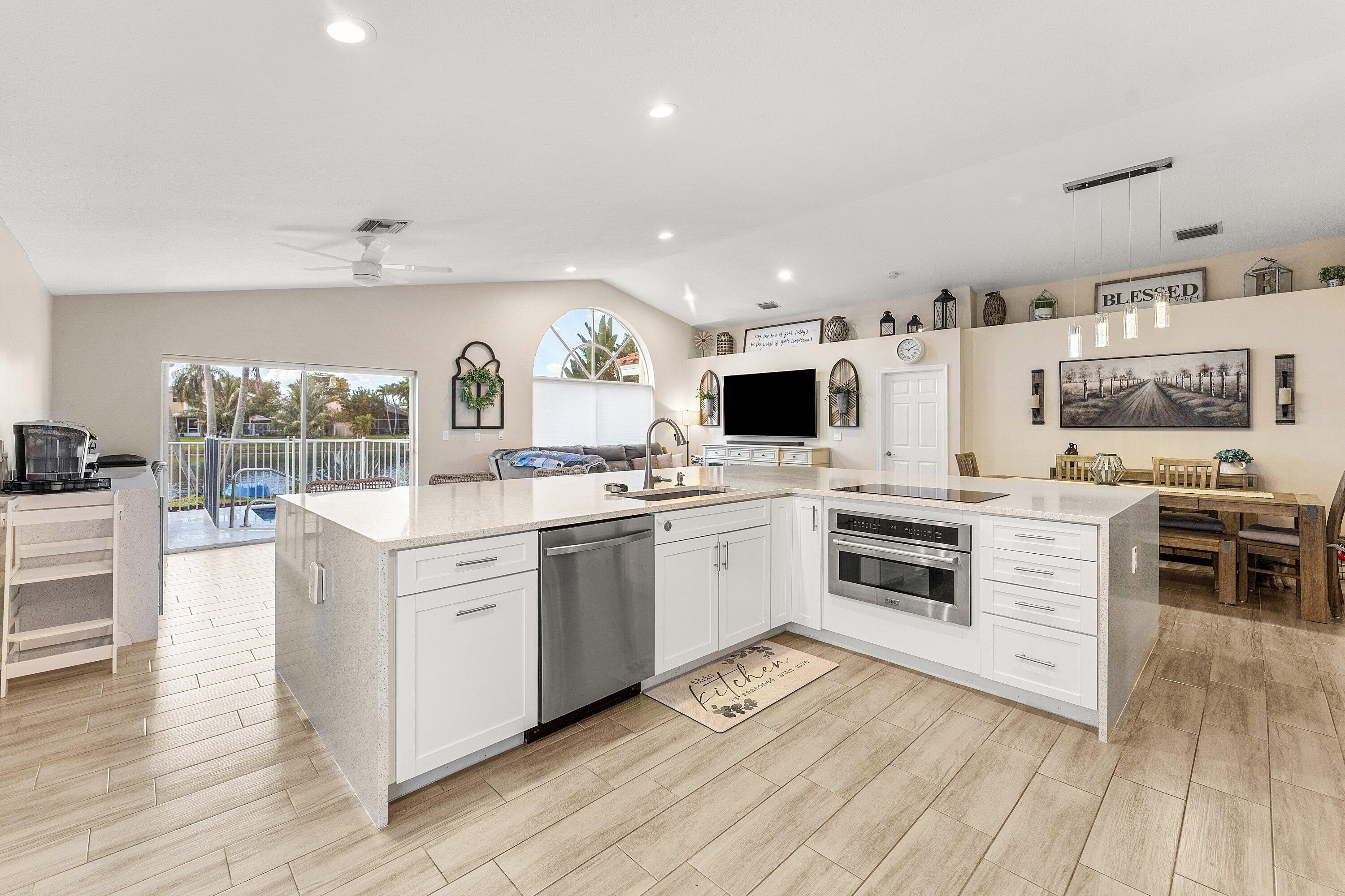 7346 Michigan Isle Road Lake Worth, FL 33467 - Photo 7 of 44 a kitchen with stainless steel appliances kitchen island granite countertop a stove and a sink