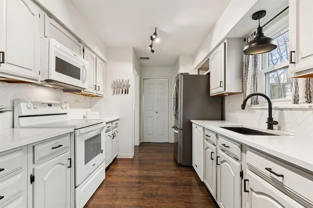 a kitchen with stainless steel appliances granite countertop a sink and a stove with white cabinets