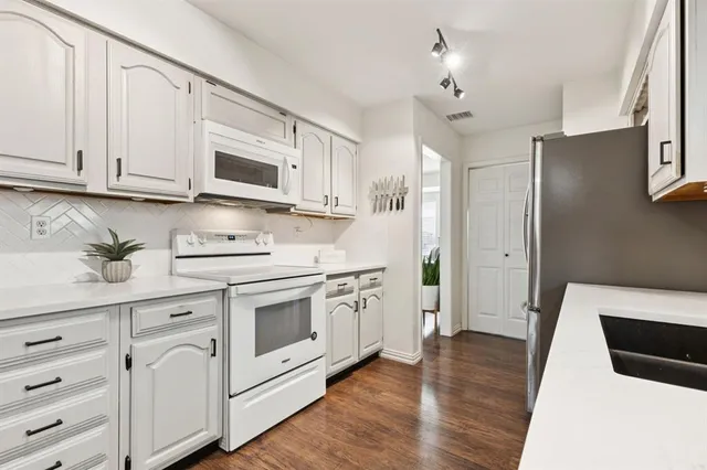 a kitchen with stainless steel appliances granite countertop white cabinets a sink a stove a refrigerator and white cabinets