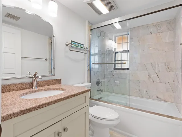 a bathroom with a granite countertop sink a toilet and shower