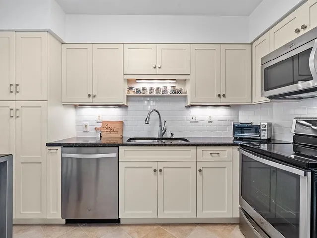 a kitchen with stainless steel appliances granite countertop a stove top oven a sink dishwasher and a microwave oven on the blue kitchen countertops