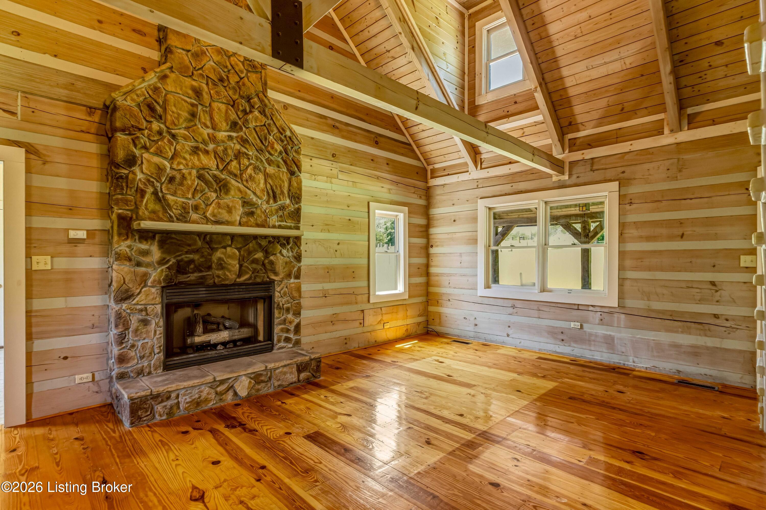 Soaring vaulted ceilings, exposed beams, hardwood floors, and a floor-to-ceiling stone fireplace.