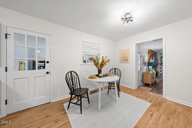 a dining room with furniture a rug a potted plant and wooden floor