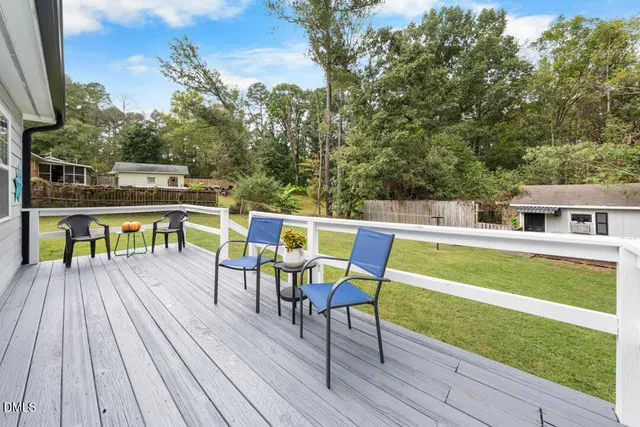 a view of a roof deck with table and chairs a barbeque with wooden floor and fence
