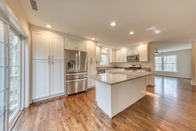 a kitchen with stainless steel appliances kitchen island granite countertop a refrigerator and a stove top oven