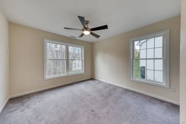 an empty room with windows and ceiling fan