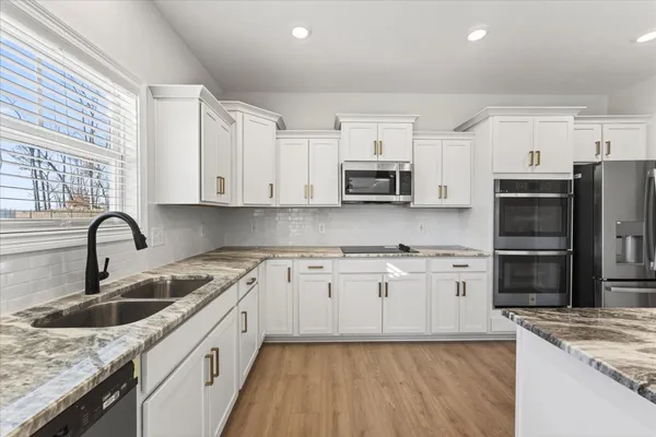 a kitchen with stainless steel appliances granite countertop a sink stove microwave and refrigerator
