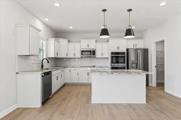 a kitchen with stainless steel appliances granite countertop a sink a stove a refrigerator and cabinets