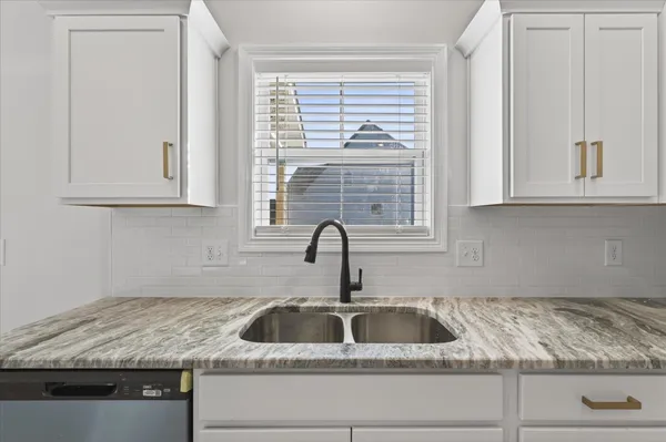 a kitchen with granite countertop white cabinets and a sink