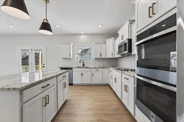 a kitchen with stainless steel appliances granite countertop a sink a stove top oven a counter space and cabinets
