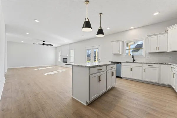 a kitchen with stainless steel appliances granite countertop a sink a stove a refrigerator and island with wooden floor