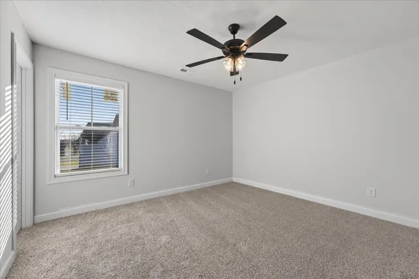 an empty room with a window and a fan