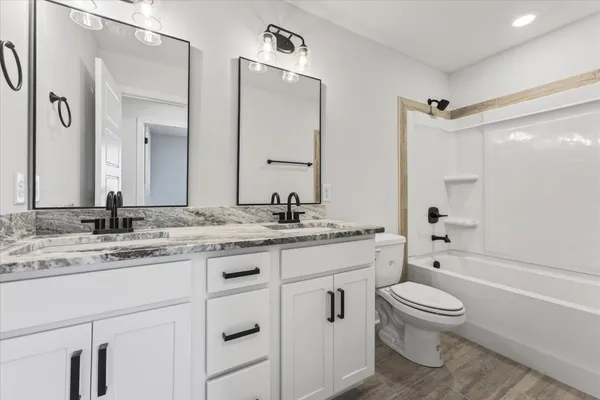 a bathroom with a granite countertop toilet a sink and a bathtub