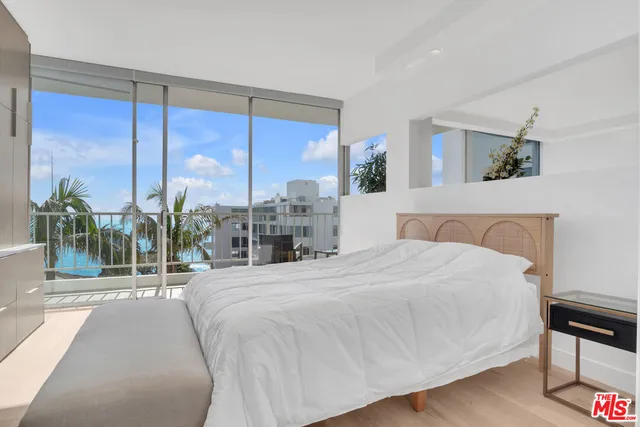 a bedroom with a large bed and a potted plant