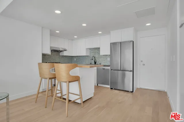a kitchen with kitchen island white cabinets and stainless steel appliances