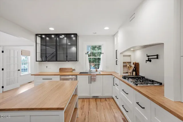 a kitchen with stainless steel appliances a stove a sink and white cabinets