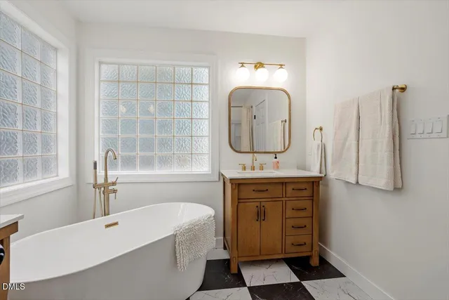 a bathroom with a double vanity sink mirror and bathtub