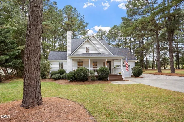 a front view of a house with garden and trees