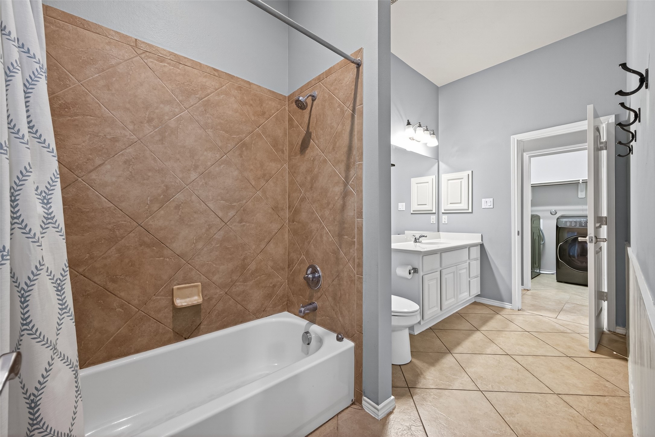 27443 Rebecca Field Lane Spring, TX 77386 - Photo 24 of 31 This is a modern bathroom featuring a tiled bathtub and shower combo, a single-sink vanity with a mirror, and a neutral color palette.